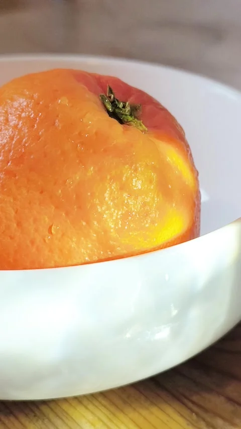 Close-up of a fresh orange fruit in a white ceramic bowl. Stock Footage 332184538