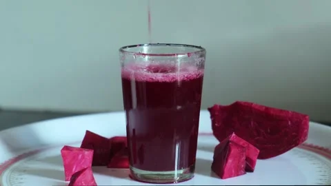 Close-up of fresh red beetroot juice being poured into a glass on a white tray Видео 329975471