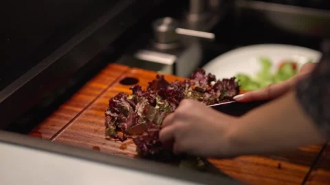 Close Up of Fresh Red Leaf Lettuce Being Chopped on Wooden Cutting Board Stock Footage 336466932