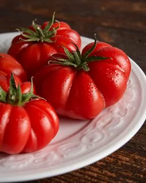 Close--up of Fresh red tomatoes raf, on white plate on wooden background. Food Stock Photos