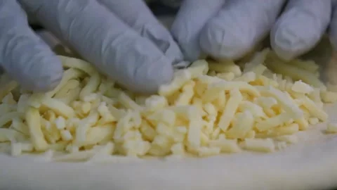 Close-up of Fresh Shredded Mozzarella Cheese Piled on Raw Pizza Dough Stock Footage 337677083