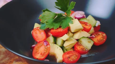 Close-up of fresh vegetable salad served in black bowl on wooden table Stockbeeldmateriaal 342823575