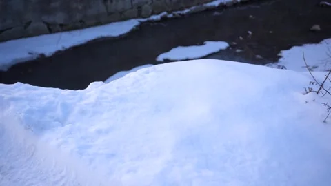 Close up of fresh white snow covering the ground near a flowing stream Stock Footage 342212227
