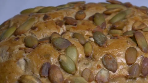 Close-up of a fresh whole grain bread roll with pumpkin seeds rotating on a.. Stock Footage 340073820