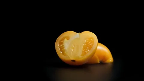 Close-up of fresh yellow cherry tomato half with smooth texture on black re.. Stock Footage 309698758