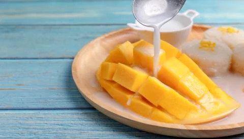 Close up Fresh yellow mango peel and Sliced cubes with sticky rice. Spoon pou Stock Photos