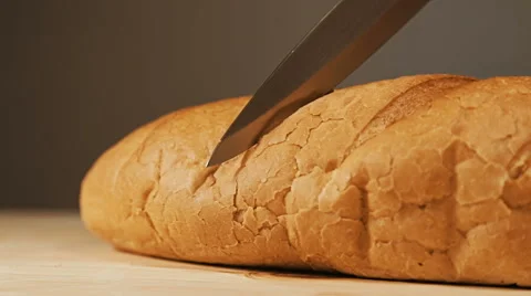 Close-up of freshly baked bread cut with a kitchen knife on a wooden table su Video stock 65003176