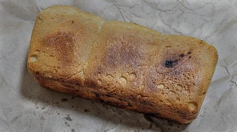 Close-up of  freshly baked loaf of bread on a sheet of kraft paper. 库存照片