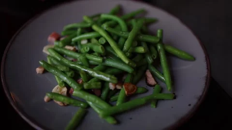 A close-up of freshly cooked green beans served on a plate. The beans are garnis 스톡 동영상 300540307