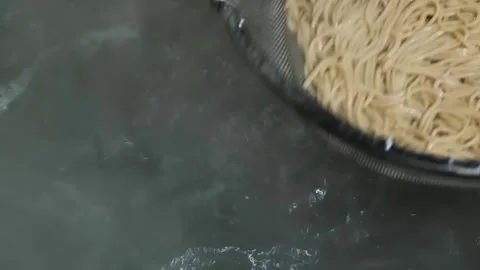 Close-up of freshly cooked spaghetti pasta draining in a metal colander, steam r Stock Footage 333600471