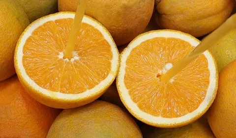 Close-up of freshly cut oranges with drinking straws in fruits, highlighting Stock Photos