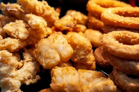 Close-up of freshly deep fried battered onion rings, shrimps and fish pieces Stock Photos