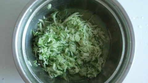 Close-up of freshly grated green cucumbers in a metal bowl Stock Footage 333633826