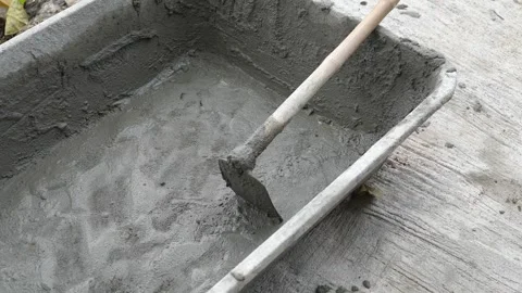 Close-up of freshly mixed wet cement in a black plastic tub with a hoe Видео 333853031