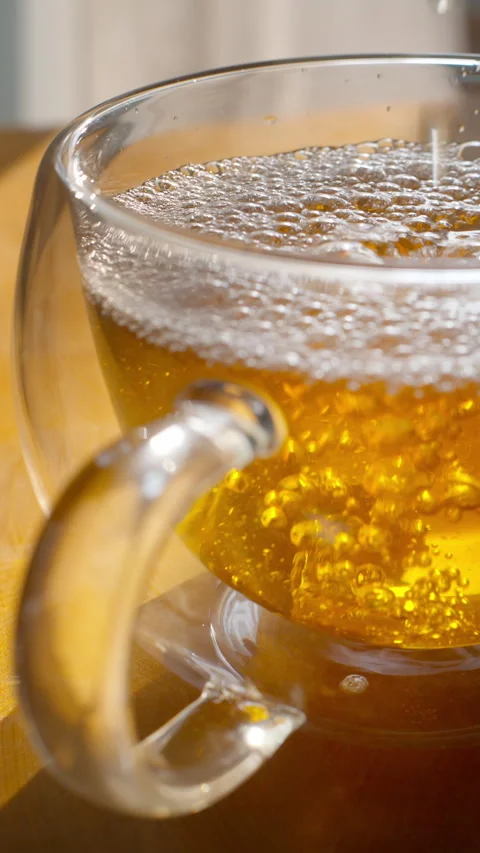 Close-up of Freshly Poured Hot Tea with Bubbles in Glass Mug Stock Footage 320926013