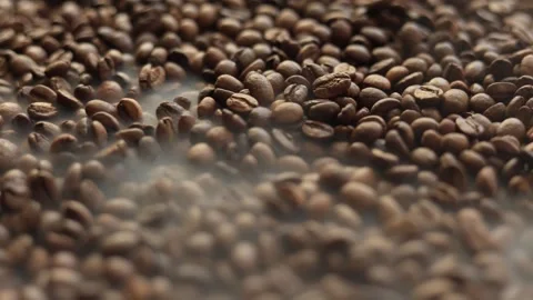 Close-up of freshly roasted coffee beans with steam rising, a warm and aromatic Stock Footage 338431382