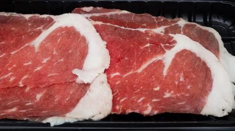 Close-Up of Freshly Sliced Marbled Beef in Black Tray Ready for Cooking Aga.. Stock Photos