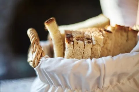 Close-up of freshly sliced white bread arranged neatly inside a woven baske.. Stock Photos