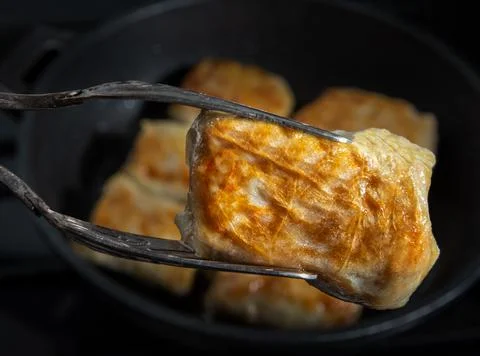 Close-up of fried cabbage roll in kitchen tongs Stock Photos