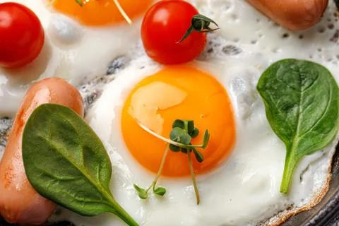 Close up of fried egg, breakfast with egg, cherry tomatoes, spinach, sausages Stock Photos