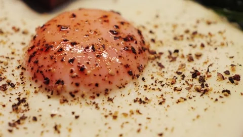 A close-up of a fried egg seasoned with ground allspice, a healthy and filling Stock Footage 331782324