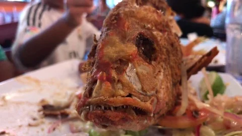 Close-up of a fried fish standing on a table and kid playing with it Stock Footage 83098885