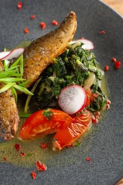 Close up of fried mackerel fish with vegetable garnish: spinach in coconut mi Stock-Fotos