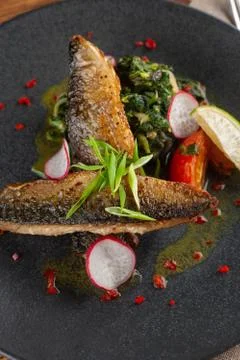 Close up of fried mackerel fish with vegetable garnish: spinach in coconut mi Stock-Fotos