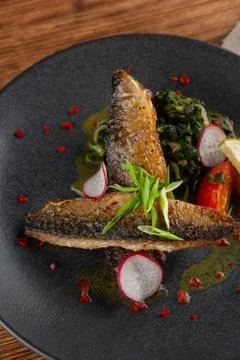 Close up of fried mackerel fish with vegetable garnish: spinach in coconut mi Stock-Fotos