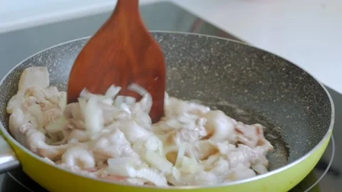 Close-up of fried meat in a frying pan a woman's hand with a wooden spatula Video stock 139587616