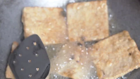Close-up of fried tempeh being flipped with a spatula. Stock Footage 329561469