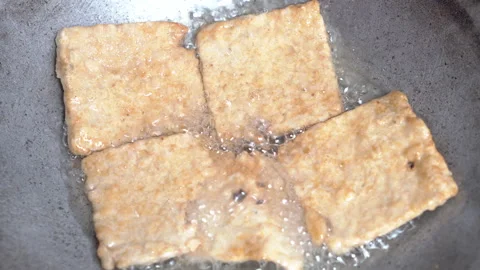 Close-up of fried tempeh coated in batter in hot oil. Stock Footage 329561479