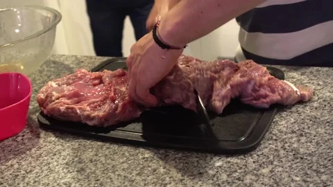Close-up of friends in the kitchen cutting meat for the grill at night in 4k Stock Footage 186218418