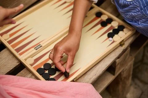 Close-up of friends playing a game of backgammon outdoors on a wooden bench Stock Photos