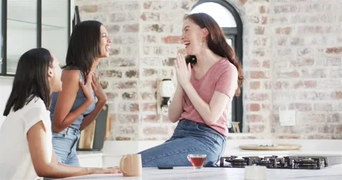 Close friends sipping tea at kitchen island noticing engagement ring hugging Stock Footage 317092658