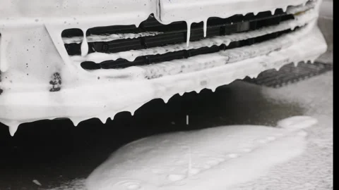 Close-up of front bumper of a car during a foam wash, with thick foam slowly Video stock 287227533