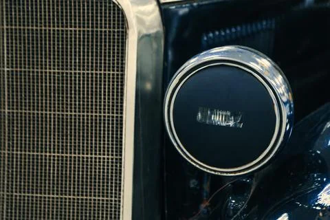 Close-up front halogen headlights and radiator of black retro car on display Foto stock