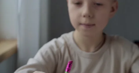 Close up front portrait of boy looking at pencil ready to draw indoors natural Stock Footage 146967521