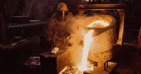 Close-up front view of a factory worker pouring molten metal into moulds Stock Footage 140734430