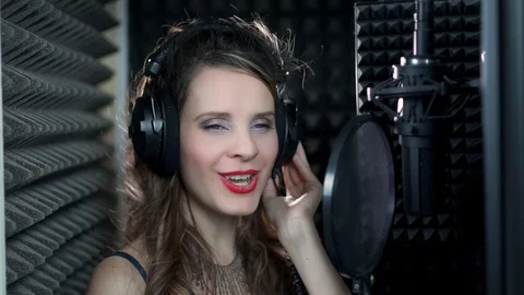 Close-up front view of a female singer in headphones singing into a microphone i Stock-Footage 119200988