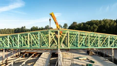 Close-up front view of green timber roof trusses being installed by a mobil.. Stock Photos
