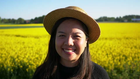 Close up front view of happy Asian woman looking at camera in yellow field Stock Footage 171643369
