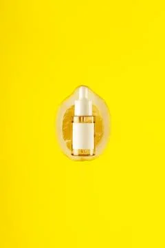 Close up front view of lemon decorated with glass cosmetic serum jar on yel.. Stock Photos