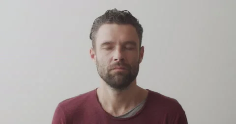 Close up front view of male face doing yoga exercises indoors on white Stock Footage 141236271