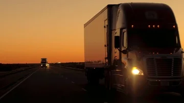 CLOSE UP Front view of semi trucks driving along the country highway at dusk Stock Footage