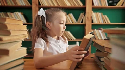 Close-up front view of serious primary child school girl flips through pages of Stock Footage 195013692
