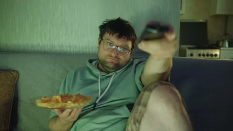 Close up front view of a tired man changing the channel with a TV remote Stock Footage 314519314