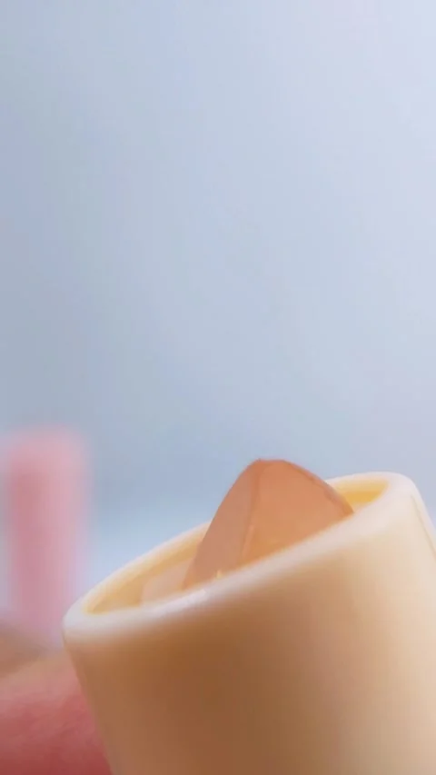 Close up front view of transparent lip balm with yellow packaging rotating .. Stock Footage 340077314