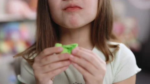Close up front view unrecognizable brunette kid girl bites pistachio green Stock Footage 194812273
