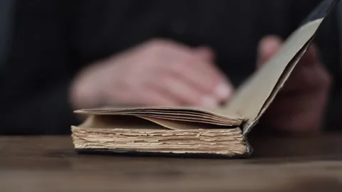 Close-up front view of unrecognizable senior aged male open old book and turning Stock Footage 169020779